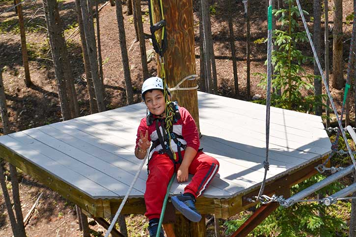 A BOEC participant waives the peace sign on the ropes course