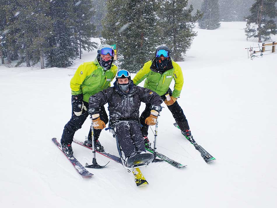 Kyle Zych poses with BOEC adaptive ski instructors