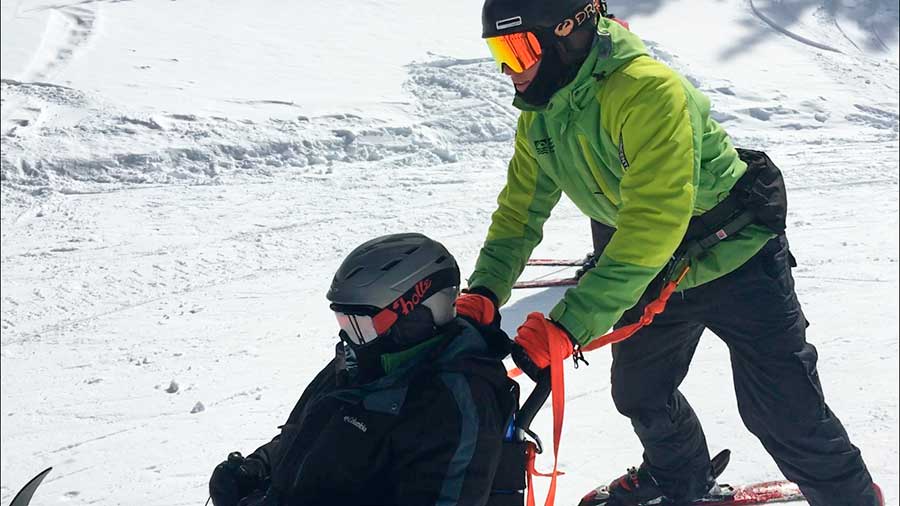 Andy propels a participant down the hill in a sit-ski during his intern program