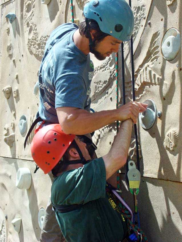 A BOEC intern assists a participant on the climbing wall as part of the BOEC Internship Program